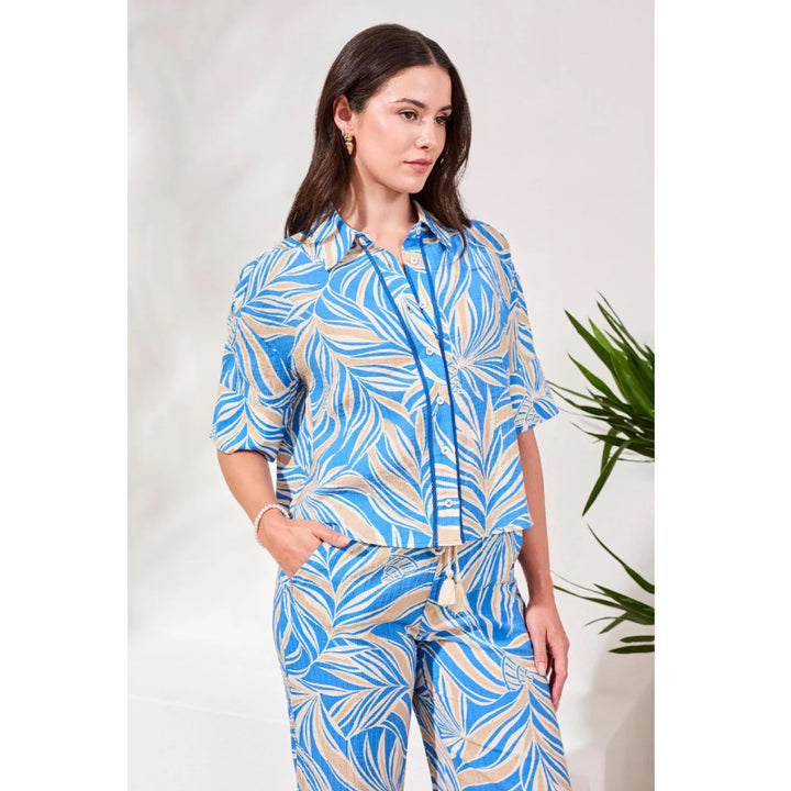 Woman wearing a blue and beige patterned outfit with a white background