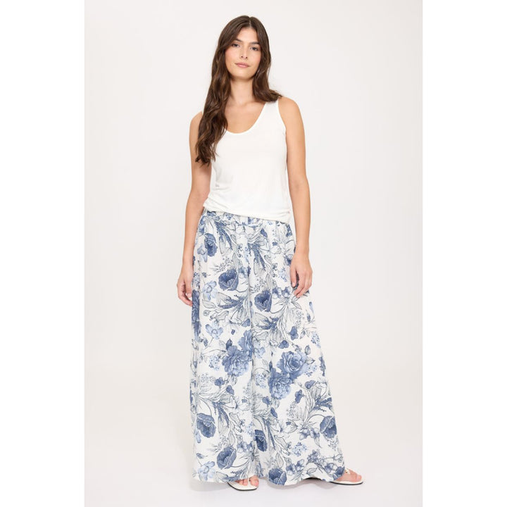 Woman wearing a white sleeveless top and blue floral long skirt on a white background