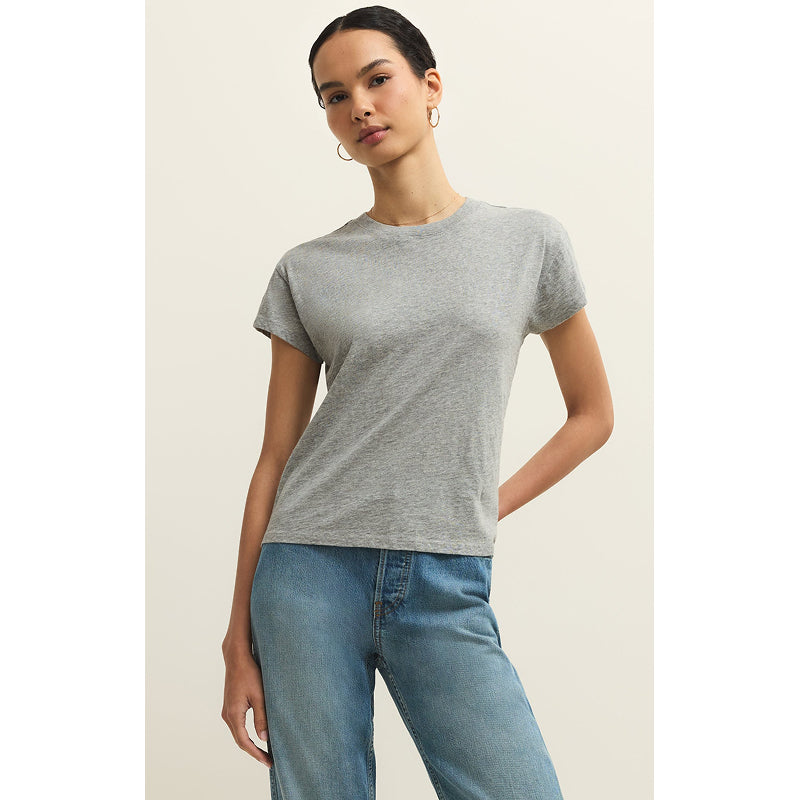 Woman wearing a gray t-shirt and blue jeans on a plain background