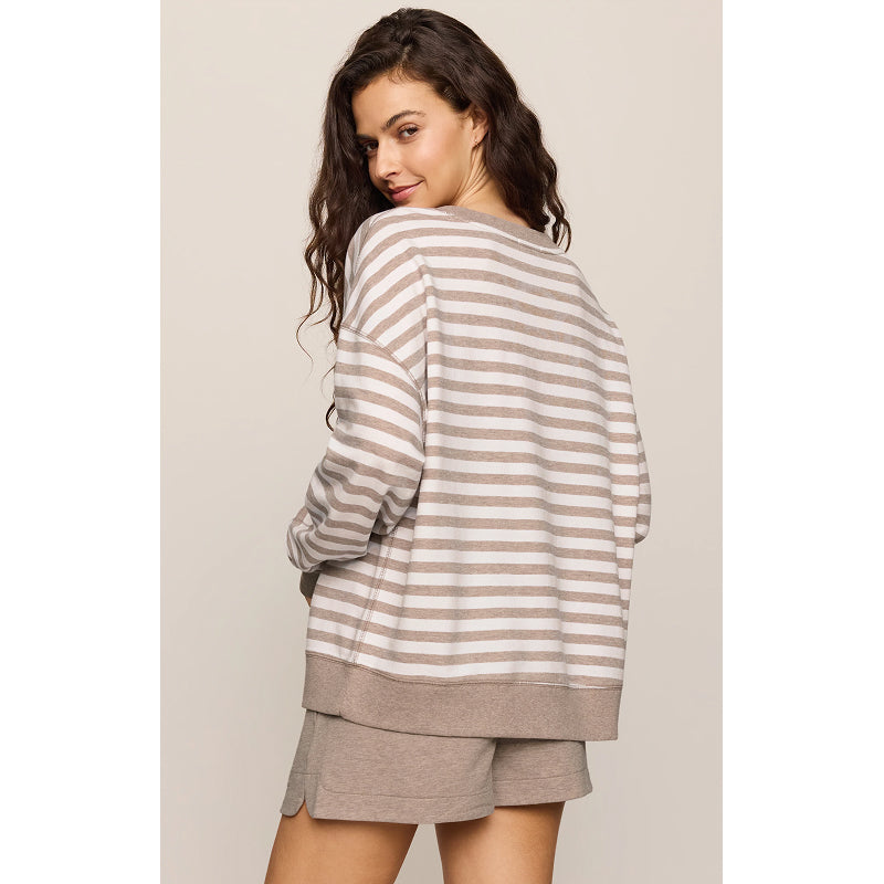 A woman wearing a loose, long-sleeve striped sweatshirt and matching shorts, photographed from the back against a plain light beige studio background.