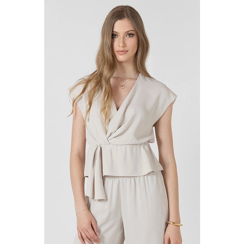 Woman wearing a beige sleeveless top and pants on a white background