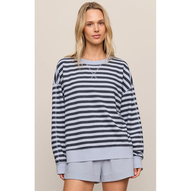 A woman modeling a navy and gray striped long-sleeve sweatshirt with a light gray ribbed hem and cuffs, paired with matching light gray shorts, against a solid beige background.