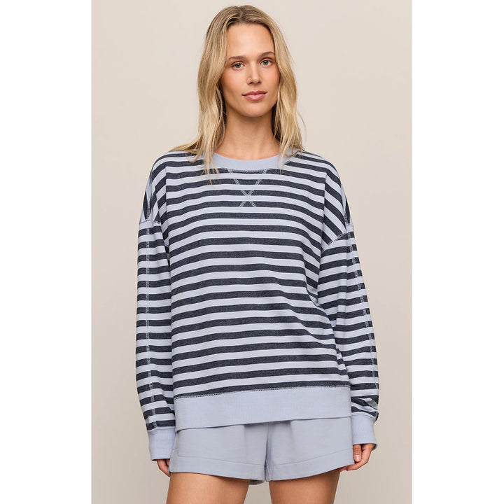 A woman modeling a navy and gray striped long-sleeve sweatshirt with a light gray ribbed hem and cuffs, paired with matching light gray shorts, against a solid beige background.