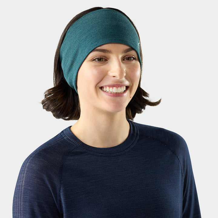Woman wearing a teal headband and navy sweater on a light gray background