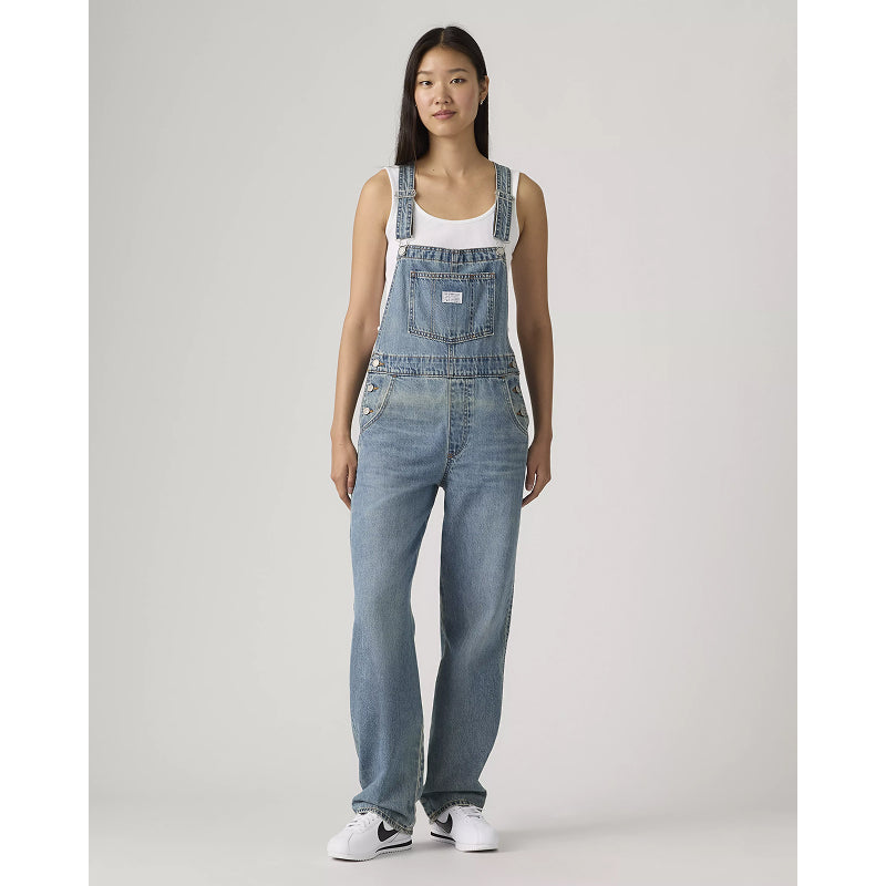 Woman wearing denim overalls on a plain background