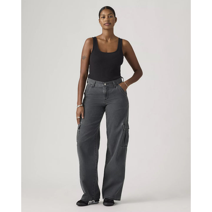 Woman wearing gray cargo pants and a black tank top on a white background