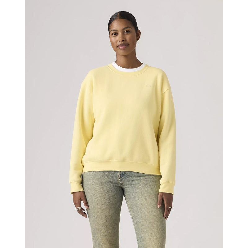 Person wearing a light yellow sweatshirt and light blue jeans on a plain background