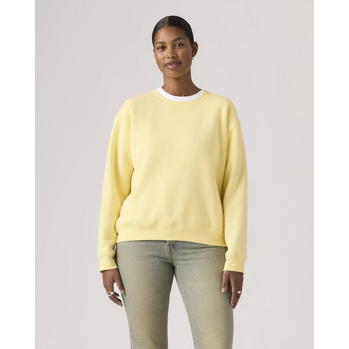 Person wearing a light yellow sweatshirt and light blue jeans on a plain background