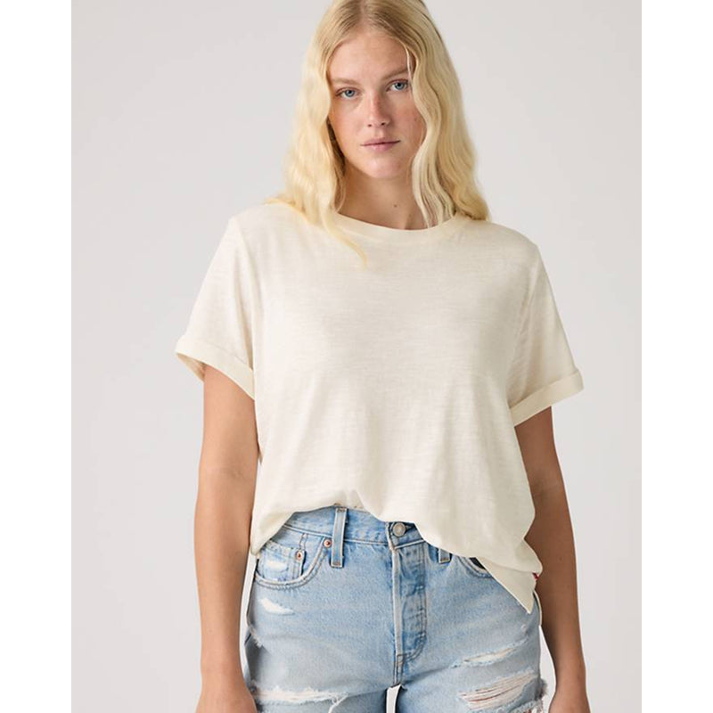 Woman wearing a white t-shirt and light blue jeans against a plain background