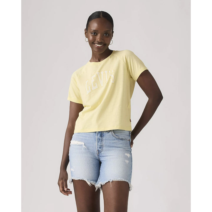 Woman wearing a yellow t-shirt and light blue denim shorts on a plain background