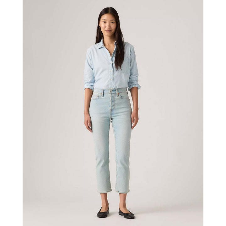 Woman wearing a light blue shirt and jeans on a plain background