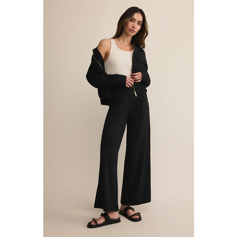 Woman wearing a black outfit with a white top against a beige background