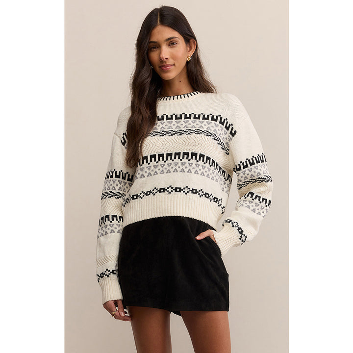 Woman wearing a patterned sweater and black skirt against a beige background