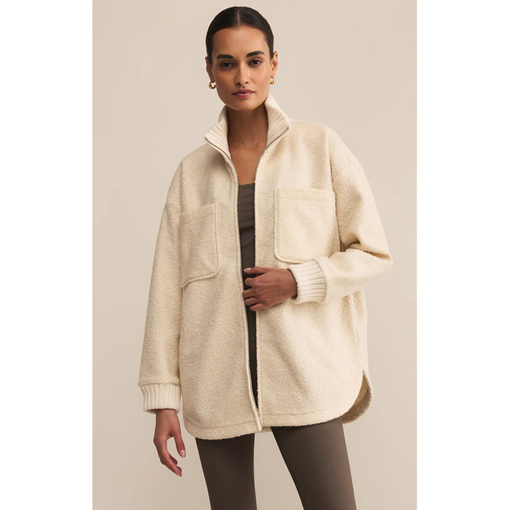 Woman wearing a cream-colored coat against a plain background