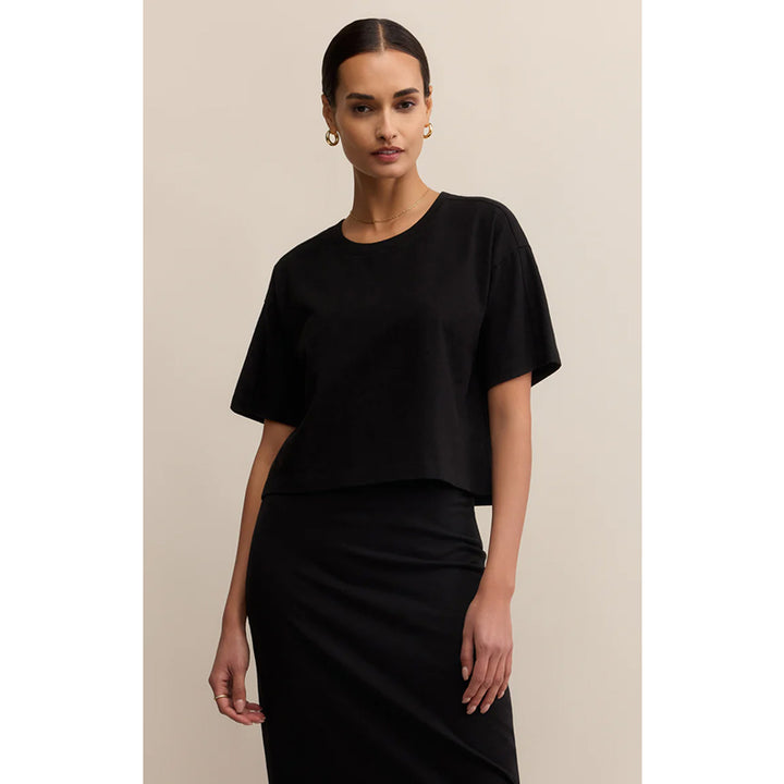 Woman wearing a black outfit against a beige background