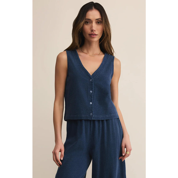 Woman wearing a blue sleeveless top and pants against a beige background